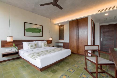 a bedroom with a large white bed and a chair at Penh House Hotel in Phnom Penh