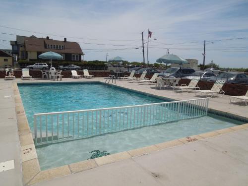 una gran piscina con sillas y sombrillas en The Jetty Motel, en Cape May