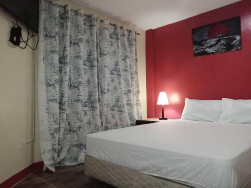 Cozy Inn Mactan في ماكتان: غرفة نوم بسرير كبير وجدار احمر