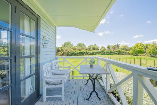 a porch with a table and chairs and a view at Bycroft Lodge in Karaka
