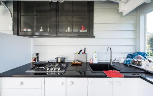 a kitchen with black cabinets and a sink at Bycroft Lodge in Karaka