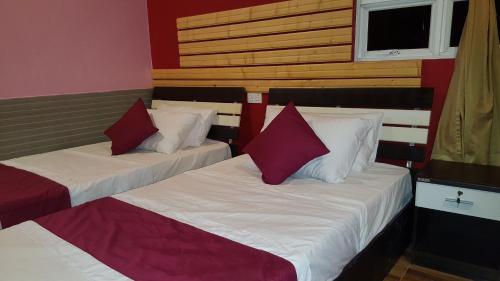 two beds in a room with red and white pillows at Finimas Residence in Thimarafushi