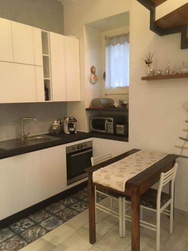 a kitchen with white cabinets and a table and a sink at Mini Appartamento Centro Storico in Pescocostanzo