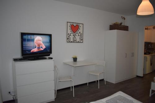 a living room with a tv on a white dresser at FeWo Köln in Cologne