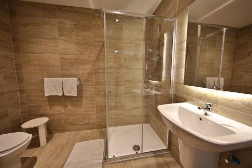 ein Bad mit einer Dusche, einem Waschbecken und einem WC in der Unterkunft Relax Inn Hotel in St Paul's Bay