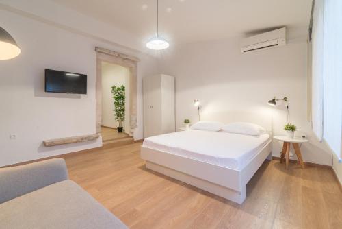 ein weißes Schlafzimmer mit einem weißen Bett und einem TV in der Unterkunft Studios & Apartments Porto in Zadar