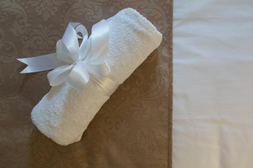 a white towel with a white flower on a wall at Studios & Apartments Porto in Zadar