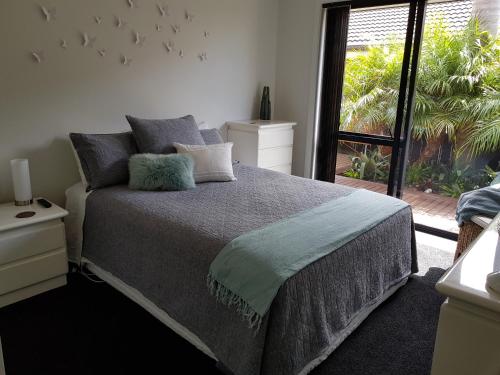 een slaapkamer met een bed en een groot raam bij Papamoa Retreat in Tauranga