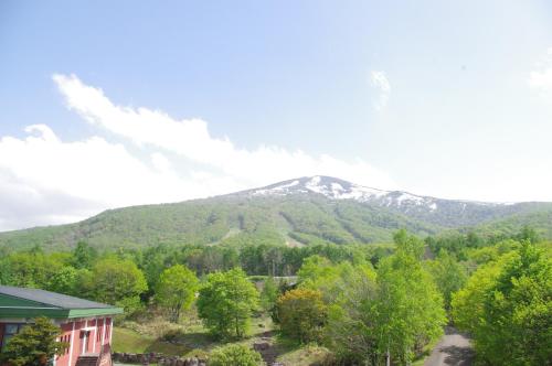 a mountain in the distance with a house and trees at Iwanai Kogen Hotel in Iwanai