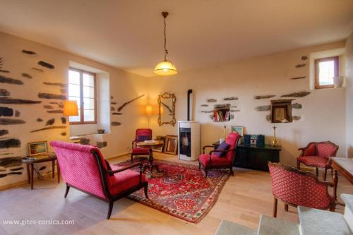 un salon avec des chaises rouges et une cheminée dans l'établissement Castellu d'Orezza, à Carcheto