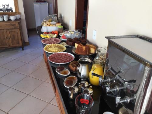 una línea de buffet con diferentes tipos de comida. en Villa Suzana, en Praia do Rosa