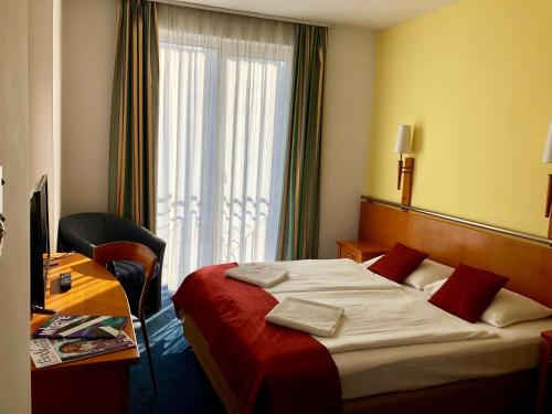 a hotel room with a bed and a desk and a window at Hotel Veritas in Budapest