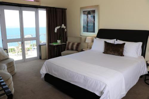 a bedroom with a large white bed and a balcony at Heaven's Window in Hermanus