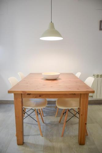 a wooden table with white chairs and a bowl on it at Modern & spacious apartment near La Concha Bay in Donostia-San Sebastián