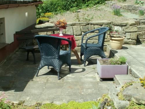 a patio with two chairs and a table with a red table cloth at Schloßblick in Lohmen