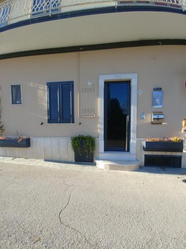 a white building with blue shutters and a door at Diadumeno Superior Apartment in Venosa