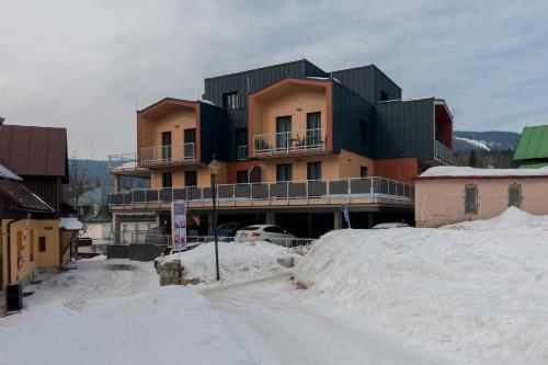 a building on a snowy street with a pile of snow at Aparthotel Residence Grand Špindlerův Mlýn in Špindlerův Mlýn