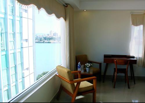 um quarto com uma grande janela com uma mesa e uma cadeira em Paradise Hotel em Da Nang