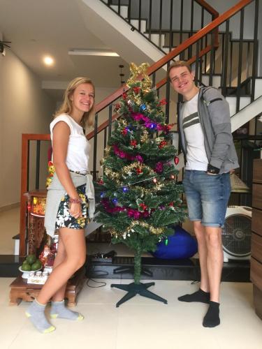 a man and a woman standing next to a christmas tree at candyinn in Hue