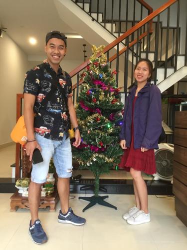 a man and a woman standing next to a christmas tree at candyinn in Hue