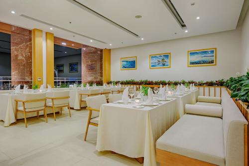 a dining room with white tables and chairs at TMS Hotel Da Nang Beach in Da Nang
