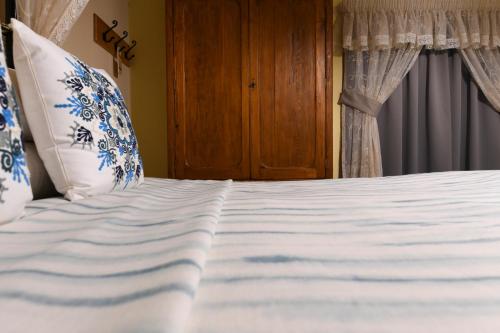 a bed with white sheets and blue and white pillows at Maria Giovanna Guest House in Marsalforn