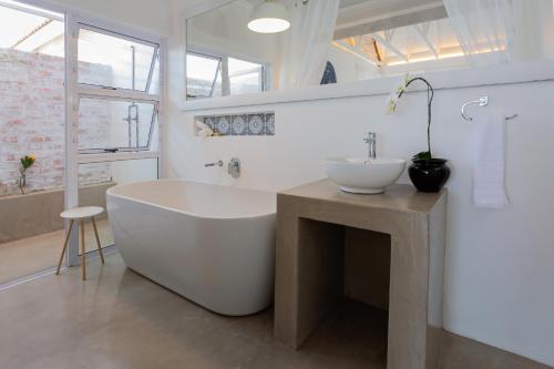 a white bathroom with a large tub and a sink at Seeplaas Guesthouse in Groot Brak Rivier