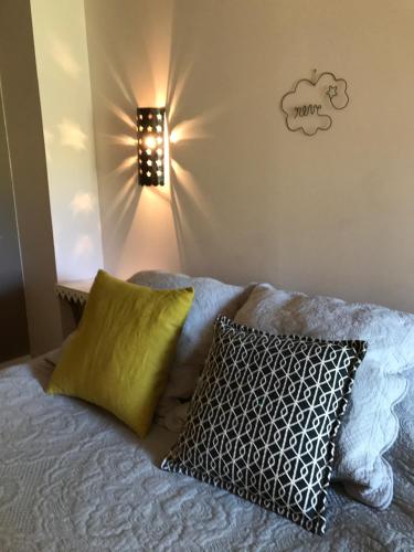 - un lit avec un oreiller et une lumière sur le mur dans l'établissement Mas Boudeissoun - Grain de Muscat - Baignade à 600 m, à Mormoiron