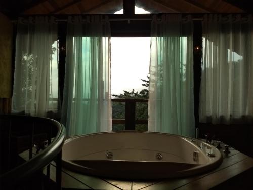 a bath tub sitting in front of a window at Chalés de Analuz in Visconde De Maua