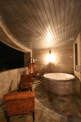 ein großes Badezimmer mit Badewanne und Fernseher in der Unterkunft WIZ Hotel in Paju