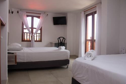 a bedroom with two beds and two windows at Akel House Hotel in Cartagena de Indias