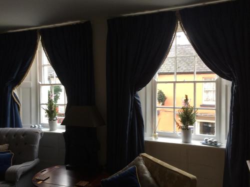 a living room with two windows with curtains and a table at Pomegranate in Coleford