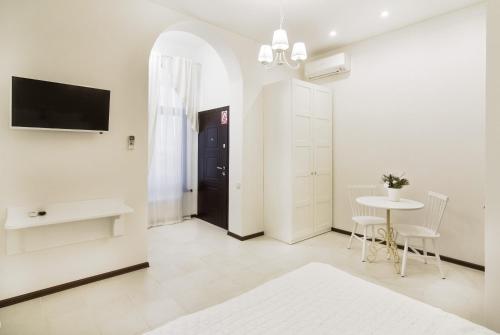 Dieses weiße Zimmer verfügt über einen Tisch und einen TV. in der Unterkunft Apart Hotel Quartet in Odessa