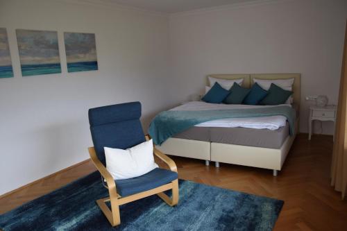 ein Schlafzimmer mit einem Bett und einem blauen Stuhl in der Unterkunft FEWO-Horgau in Horgau