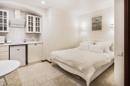 a white bedroom with a bed and a kitchen at Apart Hotel Quartet in Odesa