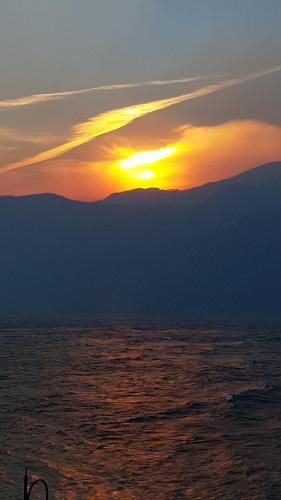 a sunset over the ocean with mountains in the background at Foresteria Lombarda La Spiaggia in Lierna