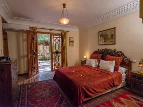a bedroom with a bed with a red bedspread at Dar Ayniwen Garden Hotel & Bird Zoo in Marrakesh