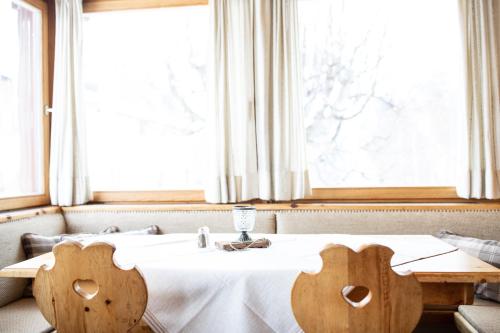 a table with a white table cloth and two wooden chairs at Meisser Lodge in Guarda