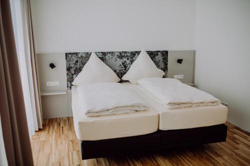a bed with white sheets and pillows in a room at Hotel Jann von Norderney in Norderney