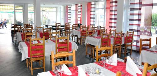 a dining room with white tables and chairs with red napkins at Hôtel de Ville in Broc