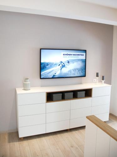 a flat screen tv sitting on top of a white entertainment center at Mountainlodge by Skischule Hermann Maier in Flachau