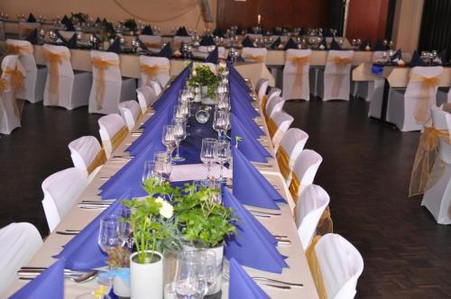 a long banquet table with blue table cloth and white chairs at Hôtel de Ville in Broc