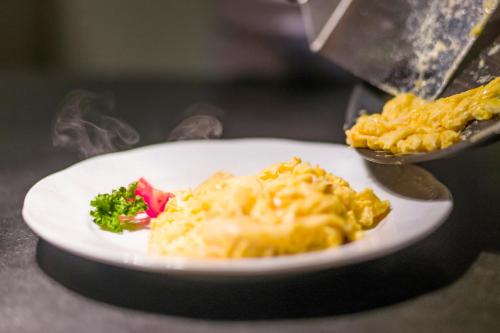 a plate of macaroni and cheese and broccoli on a table at Alpenhof Hotel Garni Suprême in Zell am Ziller