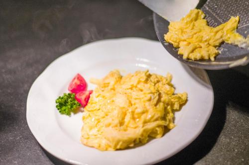 a white plate of food with broccoli and cheese at Alpenhof Hotel Garni Suprême in Zell am Ziller