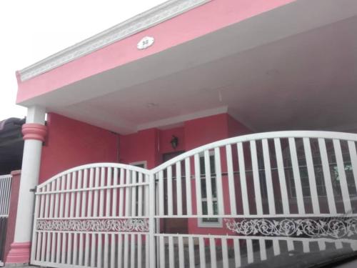 a white fence in front of a red house at Homestay Temerloh Jaya in Temerloh