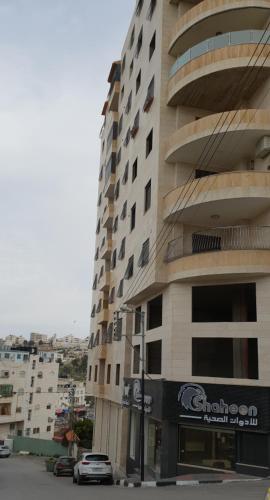 un grand bâtiment avec une voiture garée devant lui dans l'établissement Big Appatrment in Hebron Palestine Almahawer, à Hébron