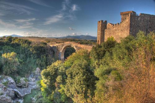 a large brick building with a bridge over a river at Resort Fonte Vulci in Canino