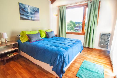 a bedroom with a bed with blue sheets and a window at Casa Neneo Bariloche 2 in San Carlos de Bariloche