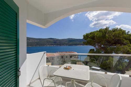 a white table and chairs on a balcony with a view of the water at Anthemis Hotel Apartments in Samos