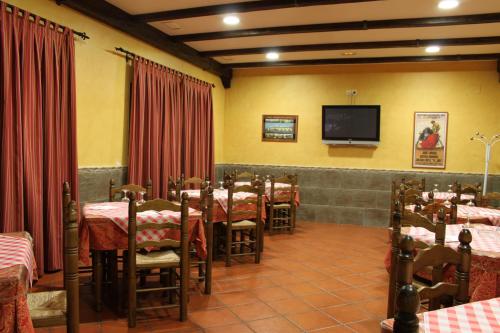a dining room with tables and a tv on the wall at Hostal Santa Ana in Madridejos